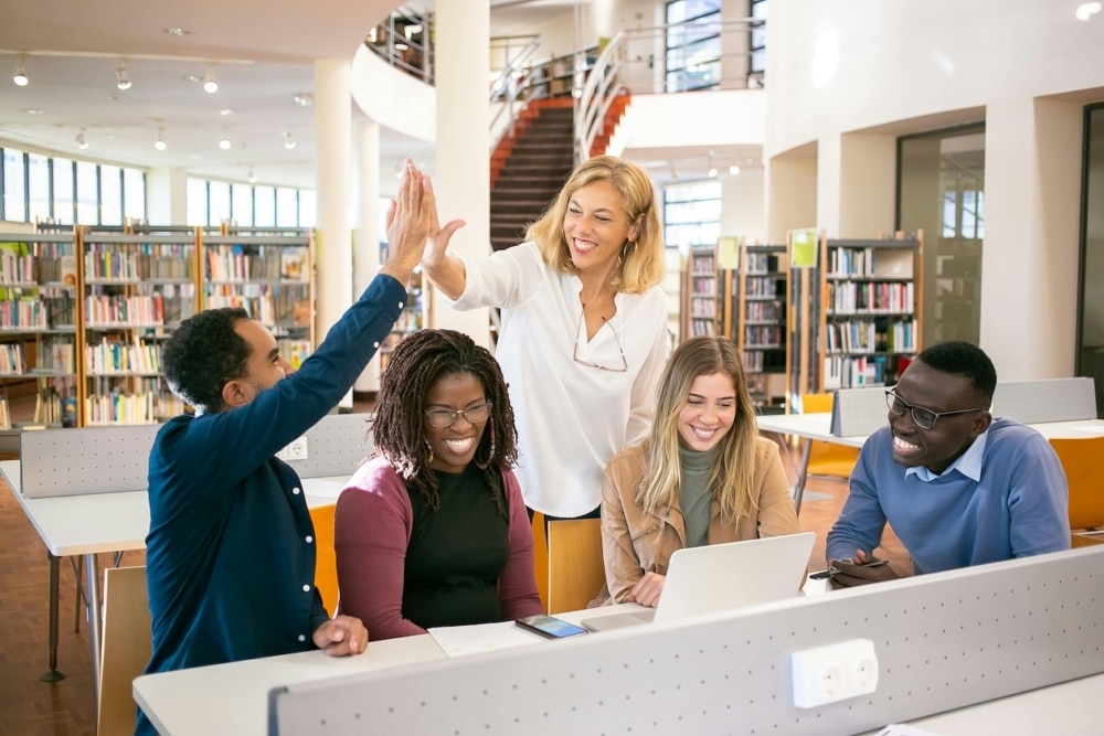 Cheerful students giving a high-five to their teacher in a classroom setting.