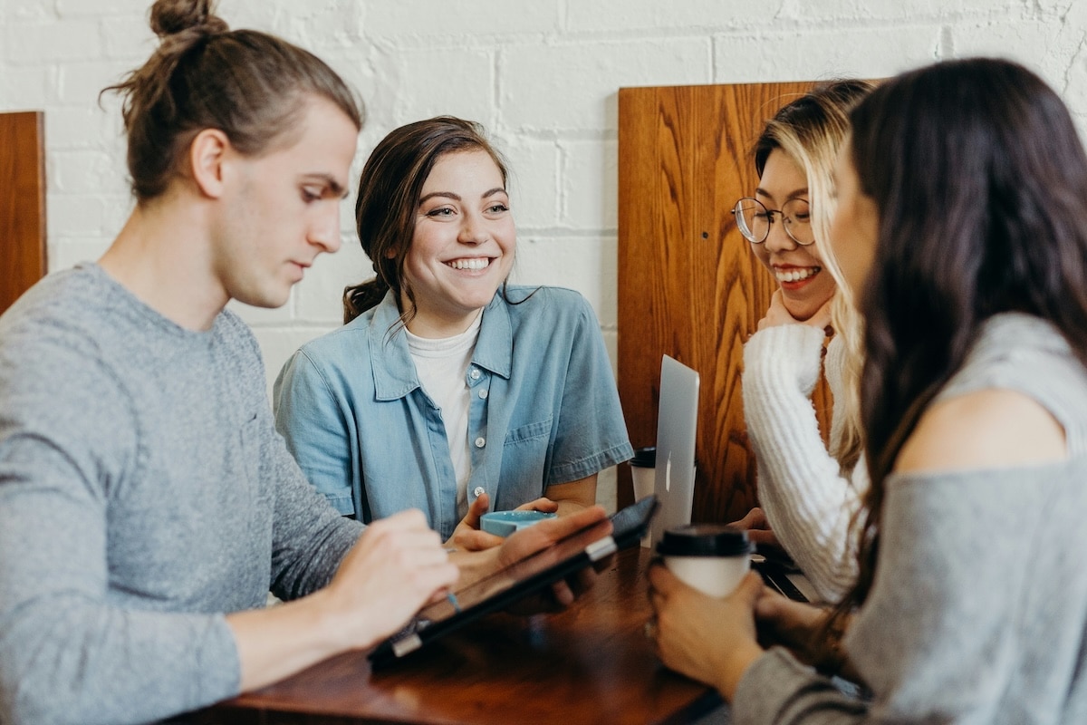 A group of friends sitting together at a coffee shop, enjoying conversation and drinks.