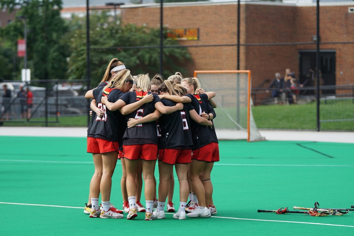 Women’s lacrosse team huddling together on a turf field before a game