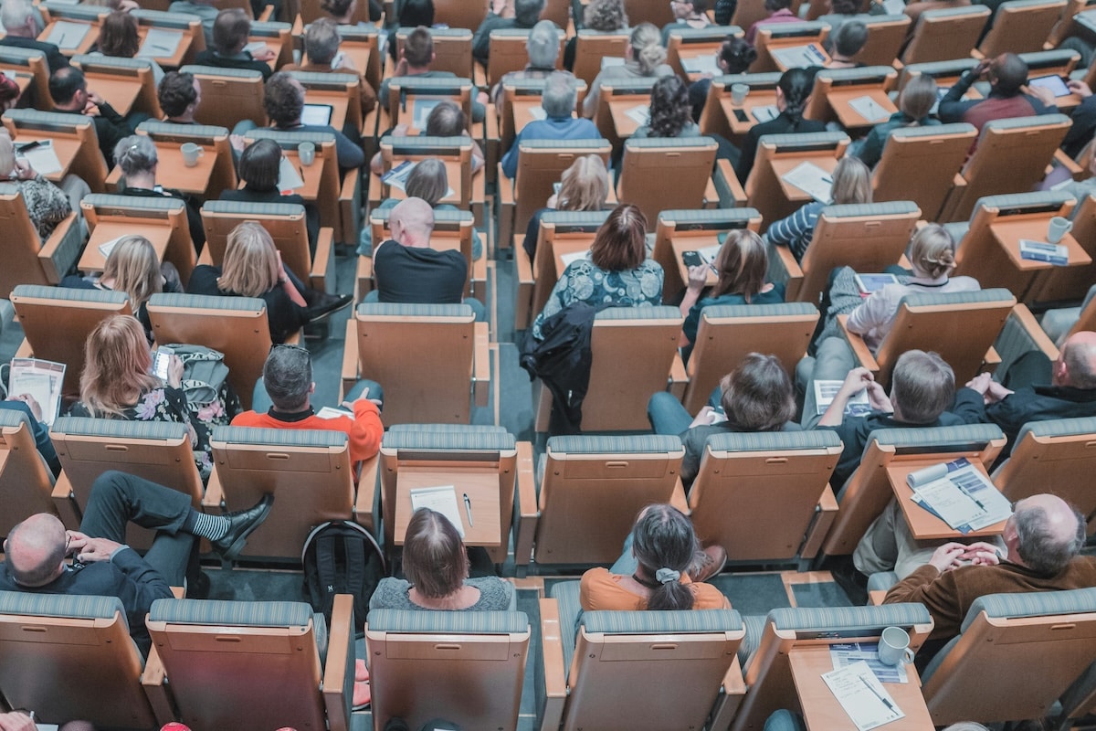 A large audience seated in a lecture hall, attending a conference or seminar.