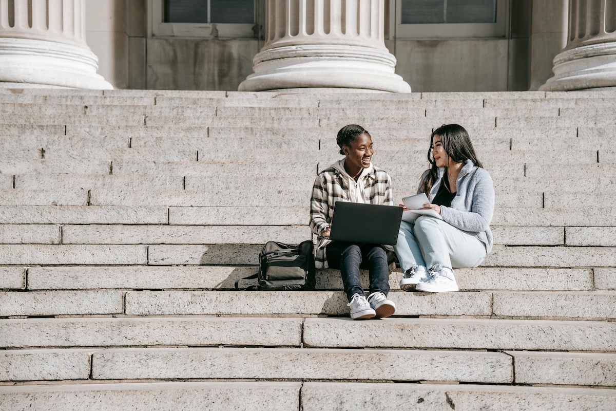 Two students studying together on stone steps outside a university building
