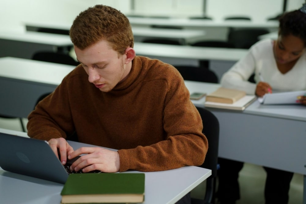Focused student working on a laptop in a classroom setting