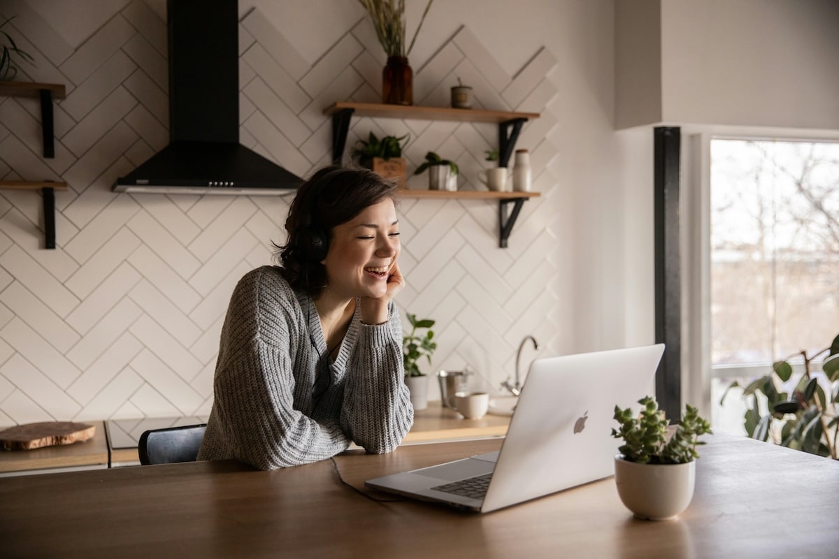 Remote Video Call from a Cozy Kitchen Space Woman wearing headphones smiling during a video call at her kitchen table