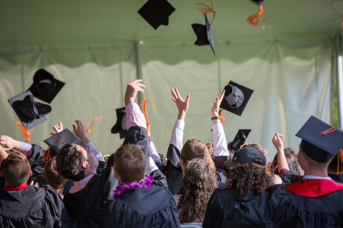 Graduates in caps and gowns celebrating by tossing their caps in the air.
