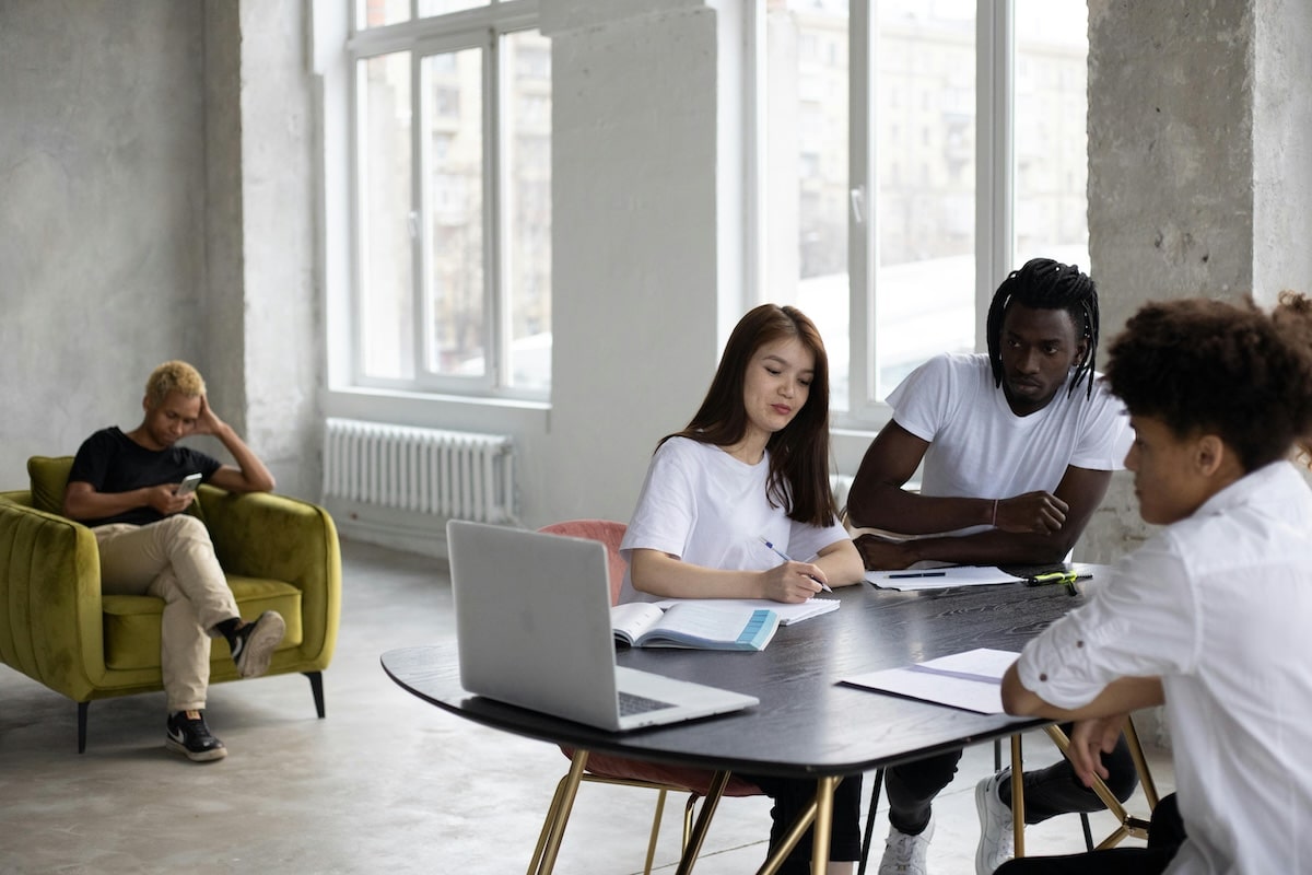 Diverse group of young adults collaborating around a table in a bright, modern workspace