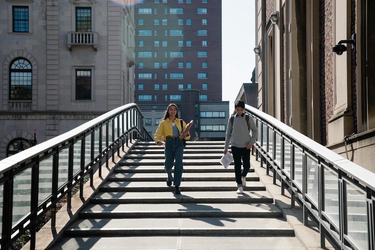 Two college students walking down campus steps between academic buildings