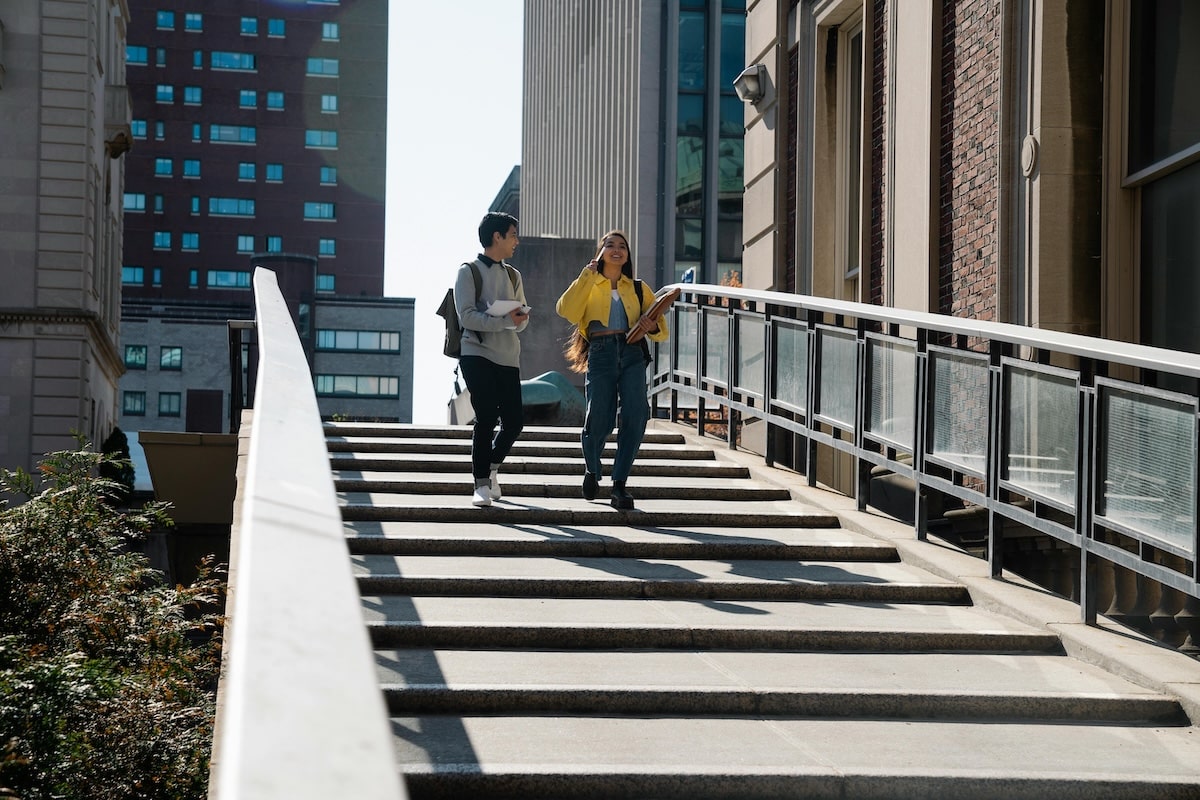 Students Leaving Campus Building Two students walking down a staircase outside a university building on a sunny day.