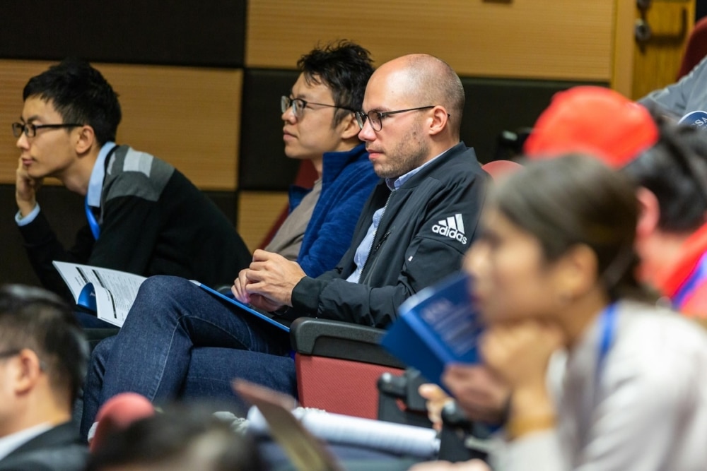 Conference attendees listening attentively in a lecture hall.