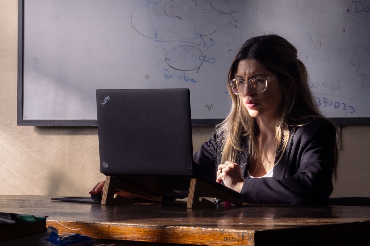 Woman reviewing data at desk, whiteboard background