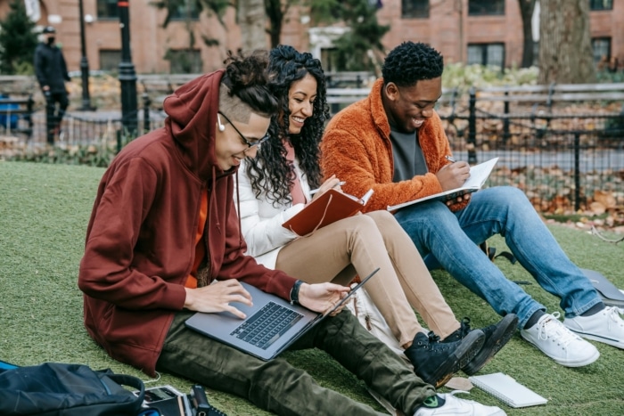Three students sit together to study and work on a project.