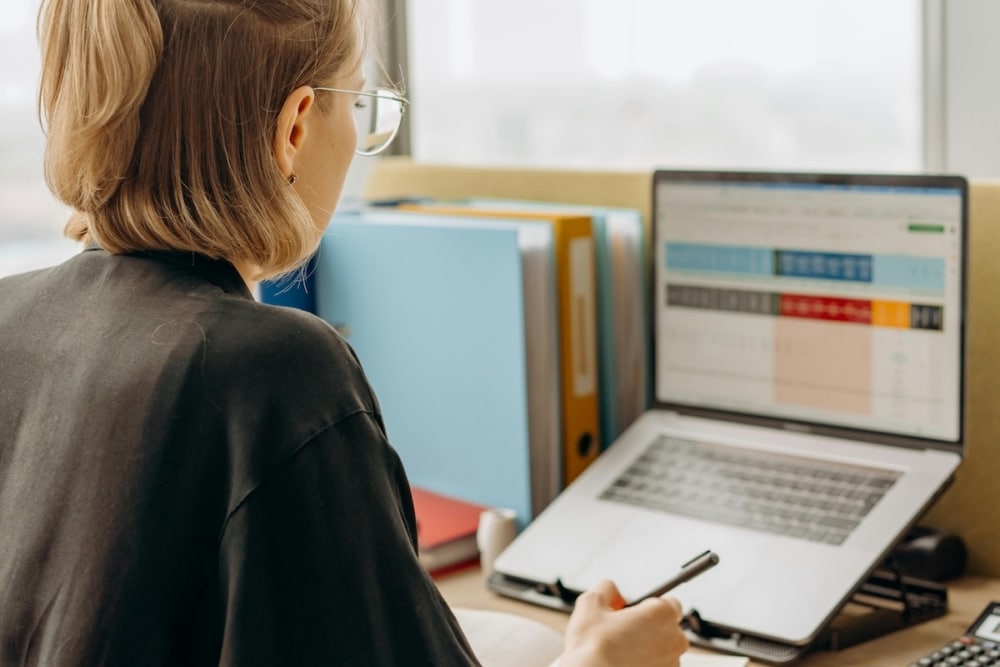 Higher education administrator reviewing enrollment data on a laptop at her office desk