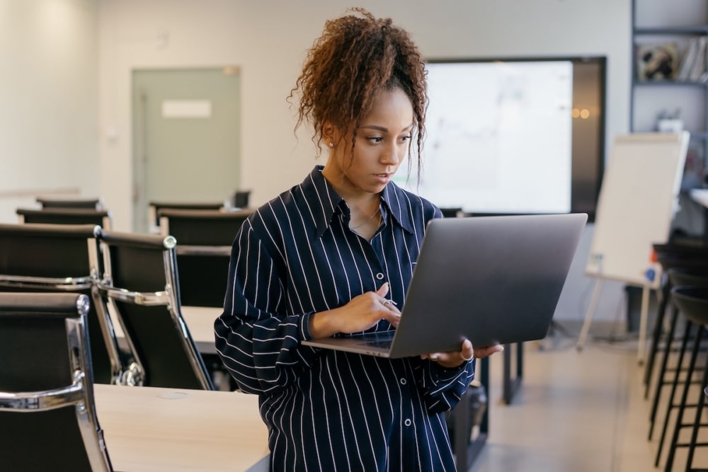 Academic advisor reviewing student messages on a laptop in an empty classroom