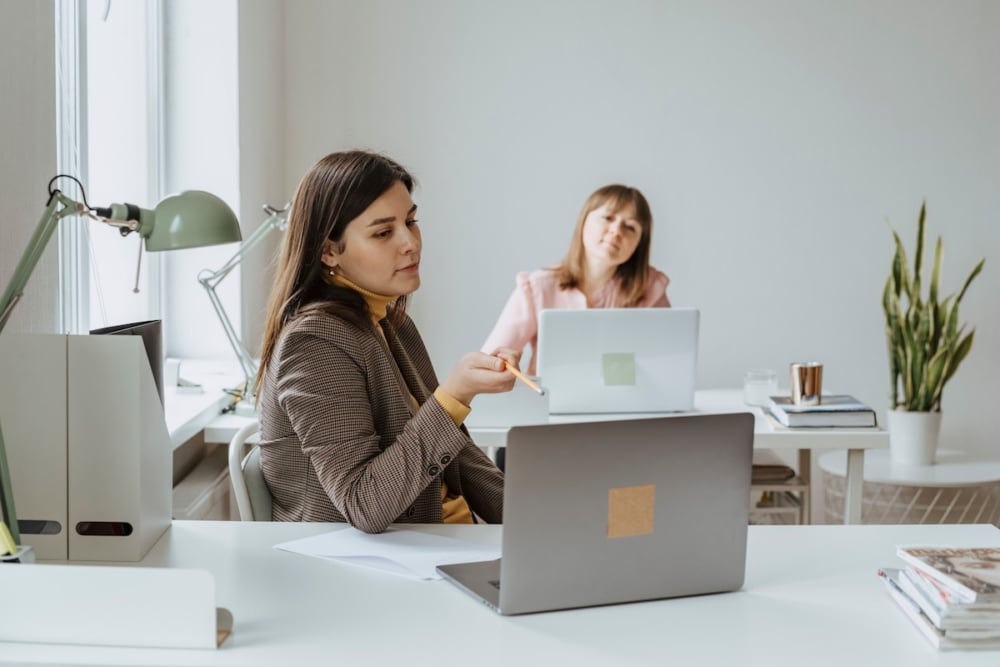 Two enrollment team members reviewing student messages together at their desks