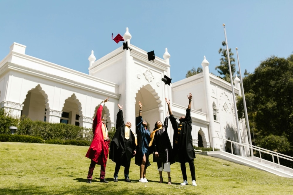 Graduates tossing caps in the air in front of a white building
